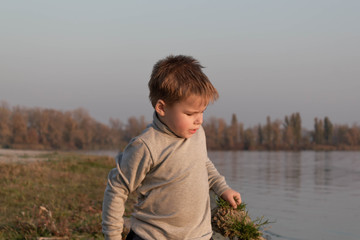 Little kid boy plays near river, lake