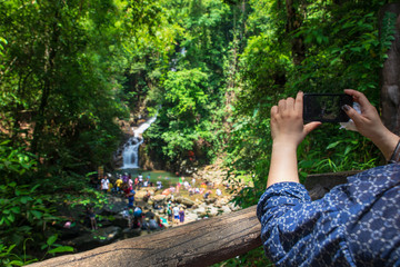 The girl taking a photo of waterfall in Thailand