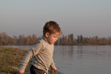 Little boy child angry, nervous, annoyed on the beach near the lake
