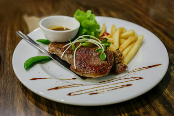 Steak premium and vegetable salad and french fried on round white plate.