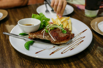 Steak premium and vegetable salad and french fried on round white plate.