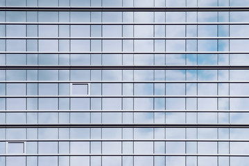 Glass facade of office buildings where the windows reflect the cloudy sky and create a perfect grid