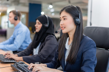 Happy smiling operator asian woman customer service agent with headsets working on computer in a call center, talking with customer for assisting to resolve the problem with her service mind