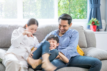 Young Asian family happy together on the sofa in the living room, Love in the family concept