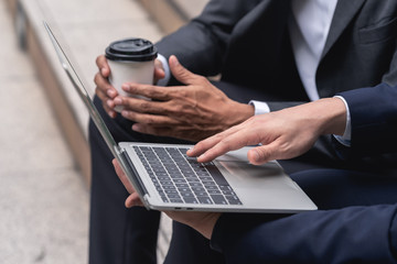 two Young businessman is typing the business performance results on laptop computer keyboard