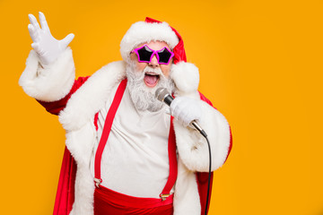 Portrait of fat big belly crazy funky santa claus hold microphones have live x-mas performance sing carols on christmas night wear red hat headwear trendy suspenders isolated yellow color background