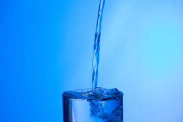 Agua entrando en un recipiente transparente de crital o plástico; agua salpicando 