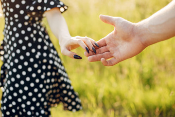 Fototapeta premium Cute couple in a park. Lady in a black dress. Guy in a black t-shirt.