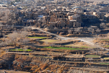 Fototapeta premium Terrace fields and ruins of medieval adobe mud-brick Kharanaq town. Iran.