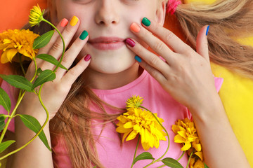 Bright and colorful children's manicure on the nails of girls with yellow flowers and good mood.