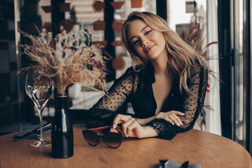 Beautiful Woman Posing in the interior. Fashionable young Woman with perfect make-up and blonde curly hair. Sexy Girl looking at the camera    