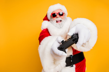 I will win. Portrait of funky funny crazy hipster santa claus play videogame use joystick having holly x-mas jolly newyear celebration isolated over yellow color background