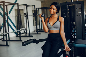 Fototapeta premium Beautiful black girl in the gym. A woman in a gray top