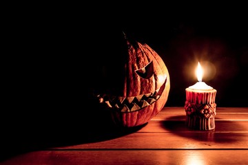 Carved spooky halloween pumpkin at hot burning candle fire flame. Big helloween autumn symbol with...