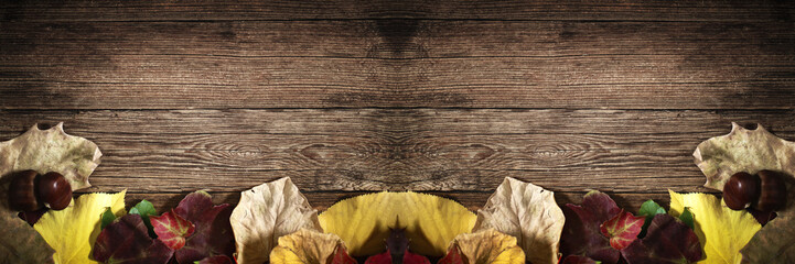 Foglie secche autunnali e castagne su sfondo in legno