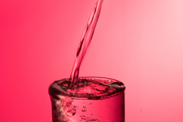 Agua entrando en un recipiente transparente de crital o plástico; agua salpicando 