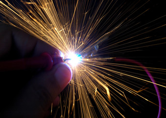 Bright burning sparks fly from the electric short contact