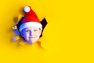 little cheerful Santa in hat smiles, getting out of the ragged yellow background lit by neon light