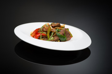 meat salad with bell pepper on a black background, isolated