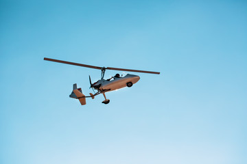 White small double gyroplane autogyro without a cabin against the blue sky. Air tours for tourists.