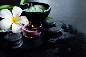 Thai Spa.  Top view of white Plumeria flower setting for massage treatment and relax on concrete blackboard with copy space.  Green leaf with black stones pile for spa therapy. Healthy Concept.