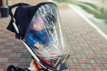 Little cute caucasian toddler boy in casual sport clothes having fun enjoy walking during rain in...