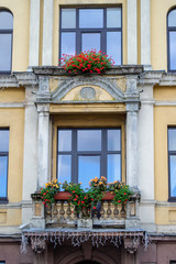 Fototapeta na wymiar Yellow wall and stone old balcony in baroque style. Pots with flover.