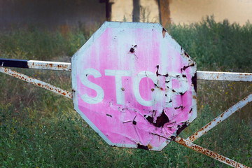 An old octagonal traffic sign without stopping is prohibited. Against the background of grass and...