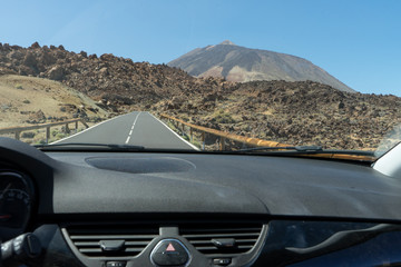 Fototapeta na wymiar Tourist inside rent a car, driving with control speed, traveling at El Teide, Tenerife. Dashboard of Automobile in Volcano asphalt motorway.