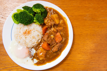 Pork Curry Rice on wooden background ( Onsen tamago, Potato, enoki mushroom, onion, broccoli, Japanese style,)