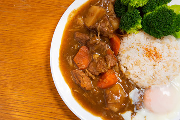 Pork Curry Rice on wooden background ( Onsen tamago, Potato, enoki mushroom, onion, broccoli, Japanese style,)