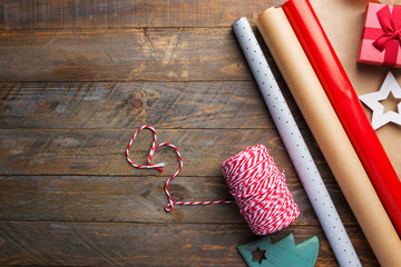 Rolls of different brown Kraft red silver wrapping paper striped ribbon gift box fir tree ornaments on wood table. Christmas New Year holiday presents shopping preparing. Rustic vintage style