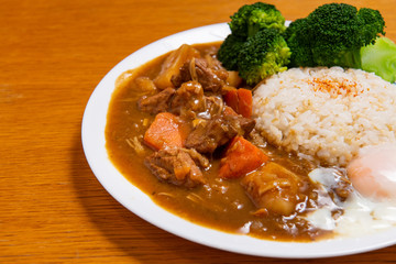 Pork Curry Rice on wooden background ( Onsen tamago, Potato, enoki mushroom, onion, broccoli, Japanese style,)