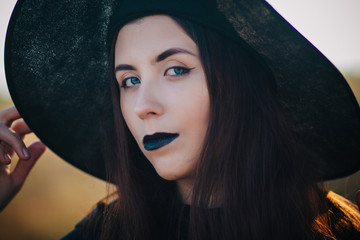 Portrait young, beautiful girl with pale skin and black lips in the form of a witch for Halloween. A model with clean skin.