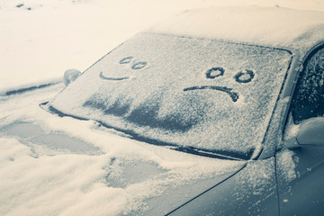 Happy and sad smiley emoticon face in snow on car windows, winter season joy and happiness concept
