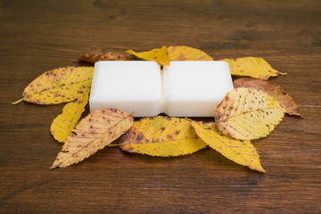 Piccolo sapone di marsiglia con foglie, isolato su un tavolo di legno in primo piano.