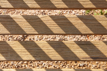 Die Sonne wirft schräge Schatten auf mehrere parallel angebrachte Holzlatten.