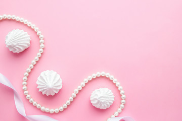 White meringue cookies with pearls jewelry and gift ribbin on pink pastel background