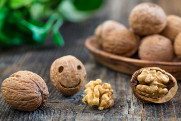 Walnuts in wooden bowl. Whole walnut on wood table with green leaves