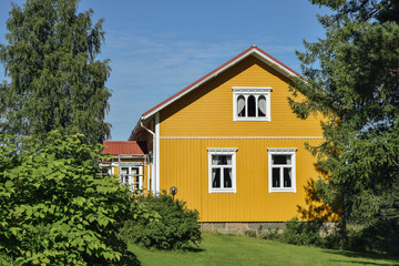 Fototapeta na wymiar Yellow wooden finnish house in countyside at strawberry farm summer sunny day with green lawn and trees