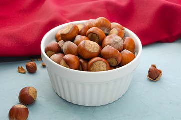 hazelnuts in white vase on the light background with red towel. close-up.