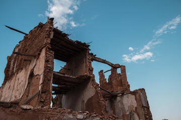 Escombros de un edificio antiguo con cielo azulado y nubes.