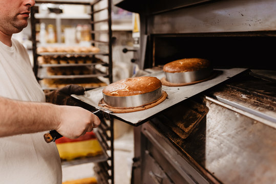 man peeking inside professional oven while working in bakery