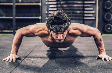 strong and athletic man doing push-up workout in modern gym