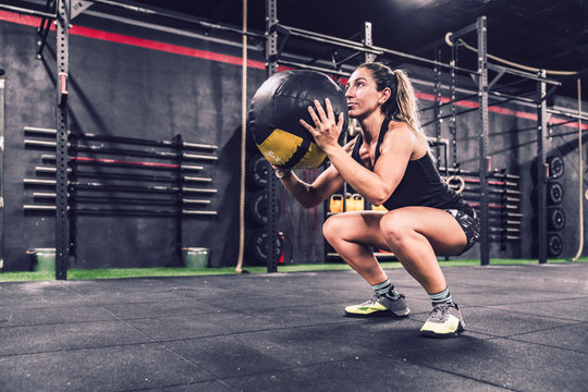 athletic female in sportswear training with fitball in health club
