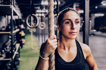 muscular woman with rope and looking way on gym