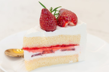 A piece of strawberry cake with cream and strawberry jam layers and topping with two fresh strawberry.