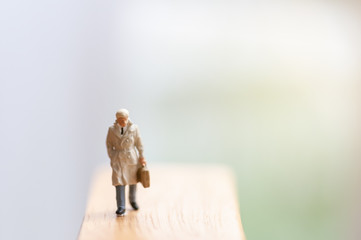 Business man stands and looks at the ground dismal, thiniking and planning to do some business. Selective focus miniature people with blur background.
