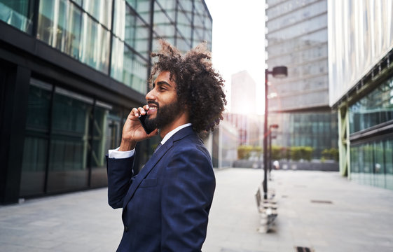 Curly ethnic man smiling at street
