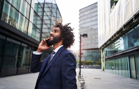 Curly ethnic man smiling at street